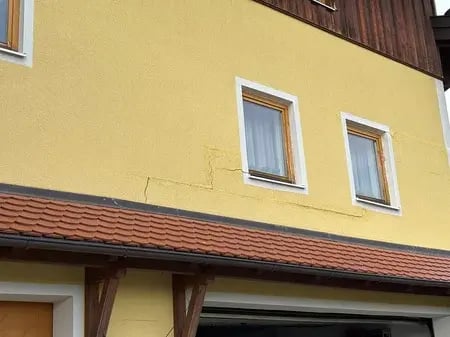 Fissuras na fachada de um edifício em forma de escada e junto à janela